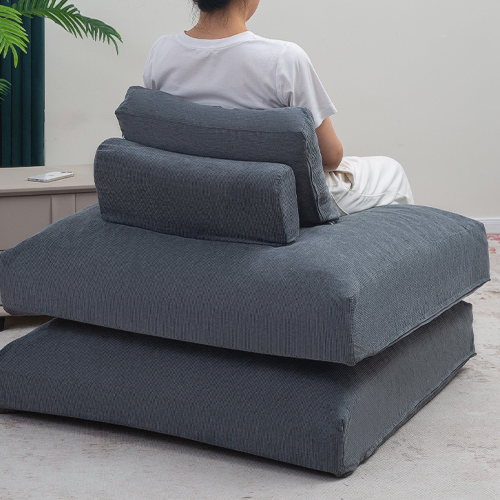 The lady is sitting on a Grey Folding Sofa folded into a floor sofa couch.